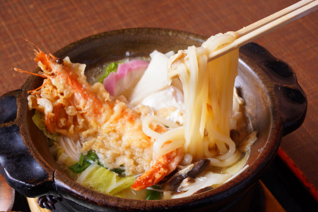 田舎家、名物の鍋焼きうどんは大きな土鍋に、打ち立てうどん麺 エビ